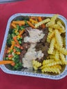 breakfast with potatoes, peas, carrots and beef in an aluminum container