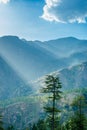 Bright sunlight shining through hole of clouds to dark scene of mountain village - India