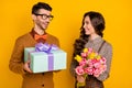 Photo of brown haired attractive couple give gift box hold flowers anniversary isolated on yellow color background