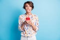 Photo of brown scared bob haired woman bite lip teeth hold hands phone isolated on blue color background