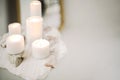 Photo of burning candles of different sizes and praying rosary beads on stand of stone and concrete