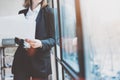 Photo business woman wearing modern suit and holding papers in hands. Open space loft office. Panoramic windows background. Horizo Royalty Free Stock Photo