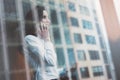 Photo business woman wearing modern suit, talking smartphone and holding papers in hands. Open space loft office. Panoramic window Royalty Free Stock Photo