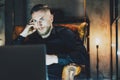 Photo businessman relaxing modern loft office. Man sitting in vintage chair at night. Using contemporarylaptop, blurred