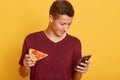 Photo of busy curious joyful teenager holding his smartphone, using his device, checking social networking sites, having piece of Royalty Free Stock Photo