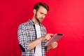 Photo of busy pretty young gentleman dressed plaid shirt spectacles browsing modern gadget isolated red color background