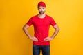 Photo of calm bearded man hands hips look camera wear red t-shirt headwear isolated yellow color background