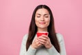 Photo of calm dreamy young woman hold hands smell coffee cup good mood isolated on pink color background Royalty Free Stock Photo