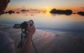 Photo camera on tripod beach sea sunset. Hobby travel photography concept. Beautiful sea landscape Royalty Free Stock Photo