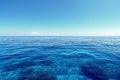 The photo captures a body of water with a vibrant blue hue, reflecting the clear sky above, An endless blue ocean under a clear