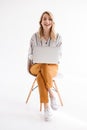 Photo of caucasian cute woman wearing casual clothes smiling at camera and using laptop while sitting in chair Royalty Free Stock Photo