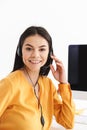 Photo of caucasian phone operator woman wearing microphone headset sitting in office and speaking with client