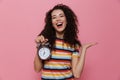 Photo of caucasian woman 20s with curly hair holding alarm clock