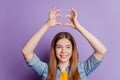Photo of charming affectionate girl making heart sign raise hands on violet background