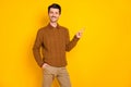 Photo of charming attarctive young man point finger index empty space hand pocket isolated on yellow color background