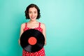 Photo of charming beautiful excited enjoying girl having found her grandpas old vynil plate while isolated with teal