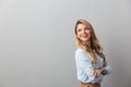 Photo of charming blond businesswoman with long curly hair smiling and standing with hands crossed near copyspace