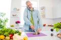 Photo of charming busy mature man dressed jeans shirt cutting vegetables calking modern gadget smiling indoors room home