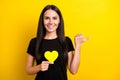 Photo of charming cheerful lady hand hold small heart card direct thumb empty space isolated on yellow color background