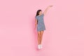 Photo of charming excited girl wear striped dress jumping high measuring empty space isolated pink color background