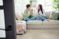 Photo of charming excited young ladies dressed shirts sitting couch telling secrets gossips indoors house room Royalty Free Stock Photo