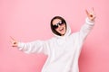 Photo of charming funky young lady wear white hoodie smiling showing hard rock sign isolated pink color background Royalty Free Stock Photo