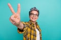 Photo of charming funny elderly lady showing v sign symbol peace gesture hippie oldschool isolated teal color background Royalty Free Stock Photo