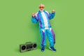 Photo of charming funny mature guy dressed blue sport suit dark glasses smiling listening boom box isolated green color Royalty Free Stock Photo