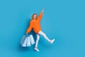 Photo of charming glad woman wear trendy orange clothes carry bags empty space isolated on blue color background