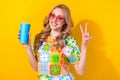 Photo charming lady drink nonalcohol cocktail paper cup show v sign wear heart sunglass print shirt yellow