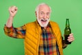 Photo of charming lucky senior gentleman wear yellow vest rising fist drinking beer smiling isolated green color Royalty Free Stock Photo