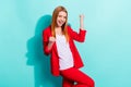 Photo of charming lucky young lady wear red blazer rising fists isolated aquamarine color background