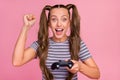 Photo of charming lucky young lady wear striped t-shirt smiling rising fist holding playstation isolated pink color