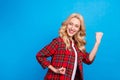 Photo of charming lucky young woman dressed checkered shirt smiling rising fists looking empty space isolated blue color