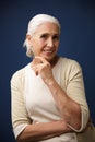 Photo of charming mature woman in beige tshirt, holding her chin