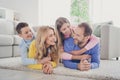 Photo of charming mom dad lying carpet hold piggyback two adorable little kids girl boy in house indoors