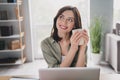 Photo of charming peaceful girl toothy smile hands hold hot fresh coffee mug imagine think workplace indoors