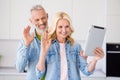 Photo of charming shiny aged couple wear denim shirt smiling waving arms modern device indoors house room Royalty Free Stock Photo