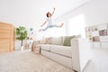 Photo of charming shiny school girl wear white t-shirt smiling jumping high sofa indoors house home room Royalty Free Stock Photo