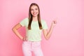 Photo of charming sweet young lady wear green t-shirt smiling pointing looking empty space isolated pastel pink color