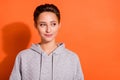 Photo of charming sweet young woman dressed grey hoodie looking empty space smiling isolated orange color background