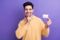 Photo of charming thoughtful man dressed yellow shirt hand arm chin rising bank card isolated purple color background