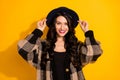 Photo of charming young lady toothy beaming smile wear black hat plaid coat  yellow color background Royalty Free Stock Photo