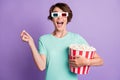 Photo of charming young woman dressed casual turquoise clothes 3d cinema eyeglasses eating popcorn isolated violet color Royalty Free Stock Photo