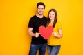 Photo of cheerfuk toothy beaming nice cute couple holding big red heart symbolizing kindness and love wearing jeans Royalty Free Stock Photo