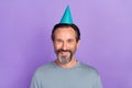 Photo of cheerful aged man have fun anniversary event birthday cap isolated over violet color background