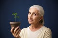 Photo of cheerful aged woman holding young plant in the spot, lo Royalty Free Stock Photo