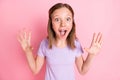 Photo of cheerful amazed little girl raise hands shocked face isolated on pastel pink color background