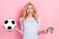 Photo of cheerful amazed young woman hold hands money football bet isolated on pink color background Royalty Free Stock Photo