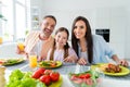 Photo of cheerful charming married couple small daughter enjoying delicious supper indoors home kitchen Royalty Free Stock Photo